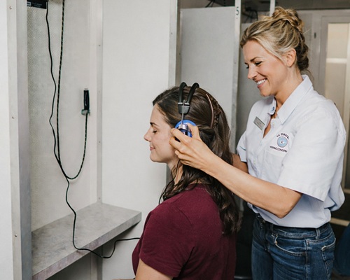 Female technician assisting test subject with headphones.