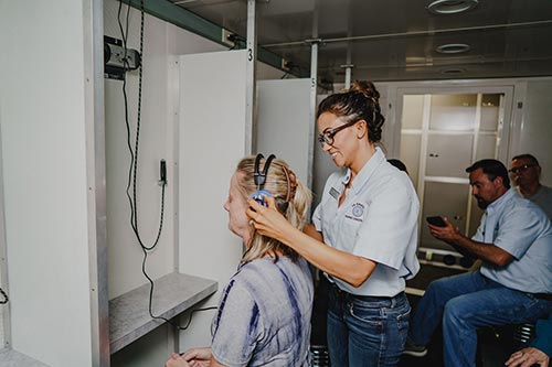 Hearing technician assists worker with headset