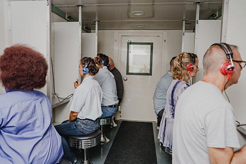 Workers taking hearing test on mobile unit
