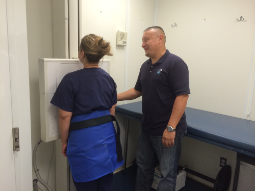 Technician assisting worker with chest X-ray