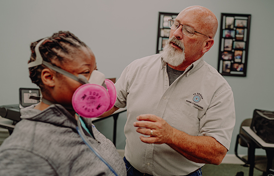 Technician assisting worker with respirator fit test